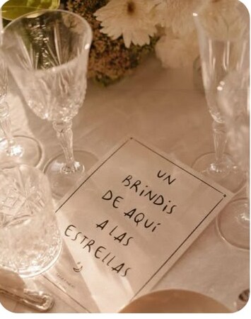 Detalle de una mesa con cristalería y una nota manuscrita